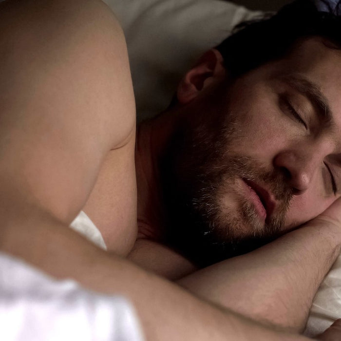 A bearded young man sleeps peacefully on his side