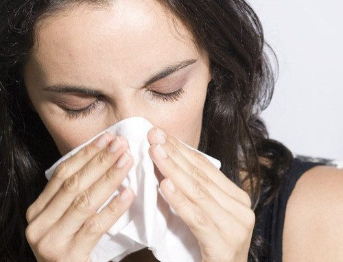 indoor allergies woman blowing nose